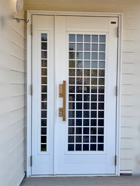 施工前の格子型の採光窓が付いた白い玄関ドア