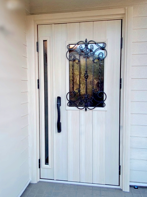 木目調のベージュ色におしゃれな装飾窓が印象的なリフォーム後の玄関ドア