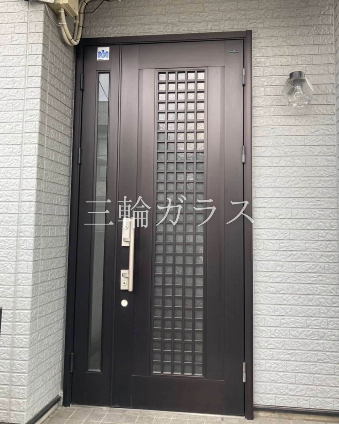 名古屋市の一戸建て住宅におけるリフォーム前の黒いアルミ製親子玄関ドア（格子デザイン・手動キー仕様）