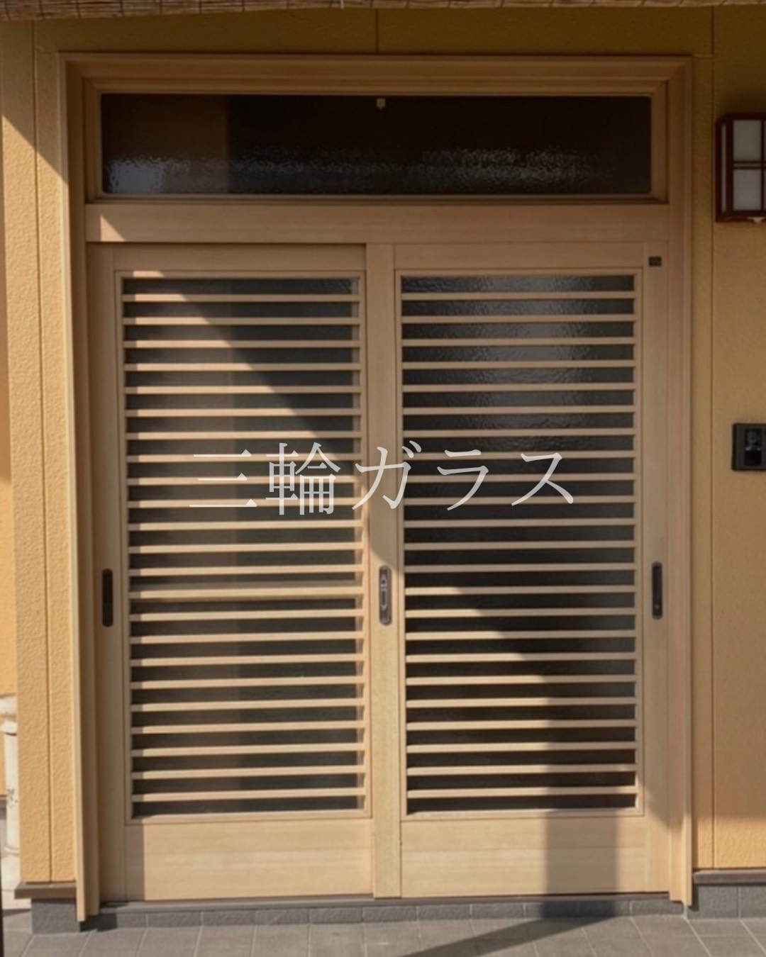 大府市の築26年木造戸建て、リフォーム前の格子デザインの玄関引き戸（隙間からペットが出てしまうお悩みがあった状態）