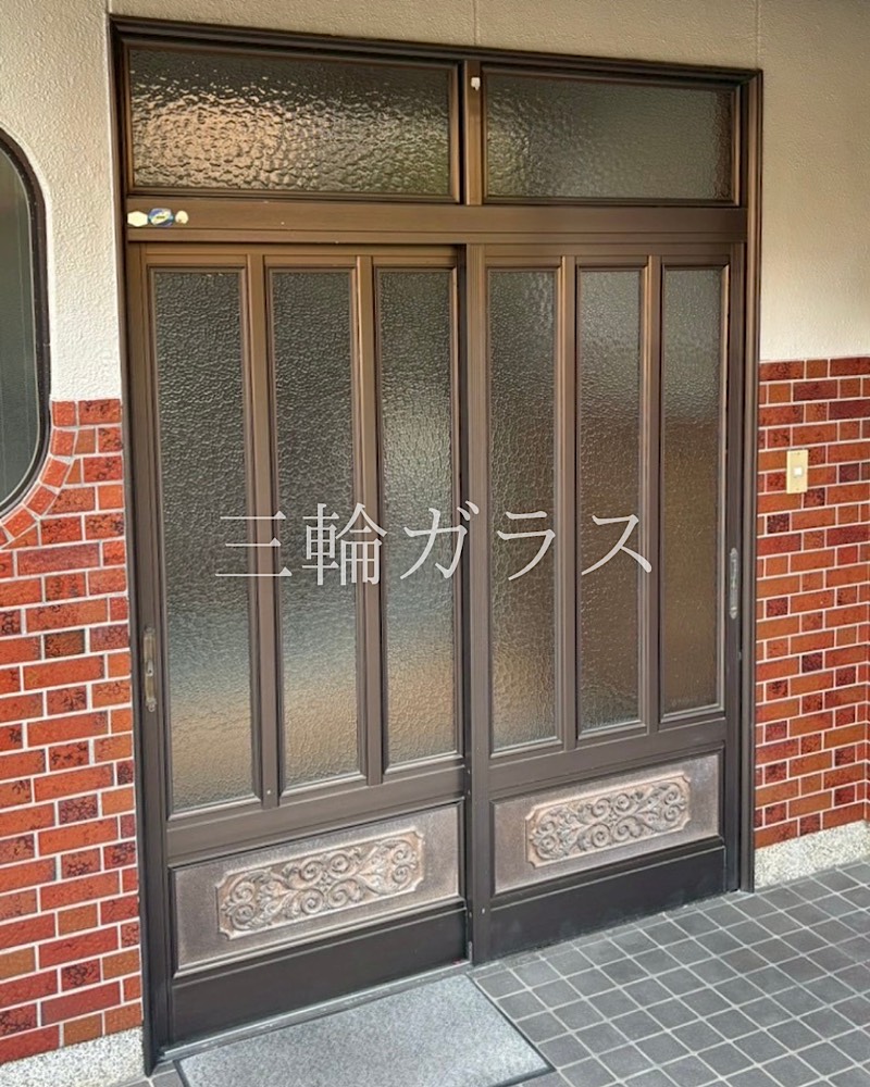 豊明市栄中学校区の玄関リフォーム前の様子。ブロンズ色の和風アルミ玄関引戸とレンガ調の外壁。